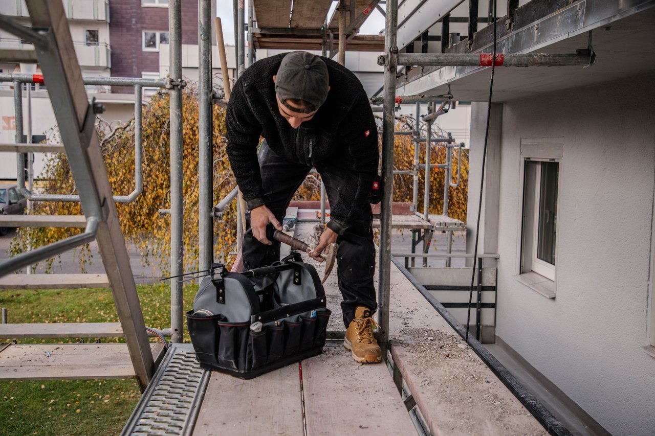 Handwerker bereitet auf dem Gerüst Werkzeug für die Balkonsanierung vor